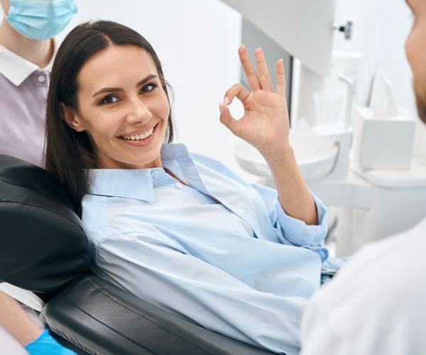 Happy dental patient using hand to make “OK” sign