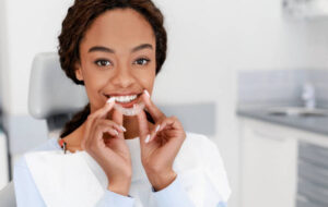 Woman at dentist holding a clear aligner